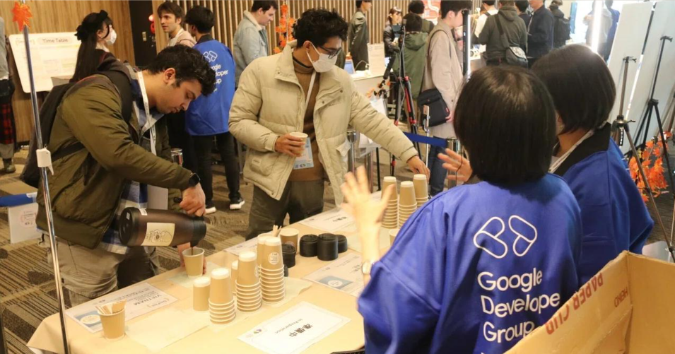 展示会でスタッフが業務用コーヒーメーカーを使い、来場者に紙カップでコーヒーを提供する様子